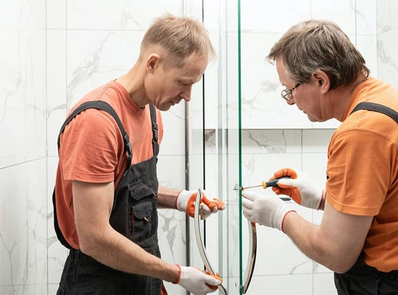 Two professional technicians repairing the shower door.